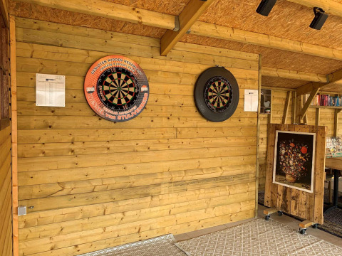 Área de dardos interior con dos tableros en la pared de madera en Camping De Grienduil, un parque vacacional en Utrecht, Países Bajos.