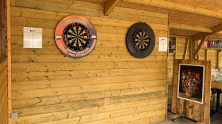 Área de dardos interior con dos tableros en la pared de madera en Camping De Grienduil, un parque vacacional en Utrecht, Países Bajos.