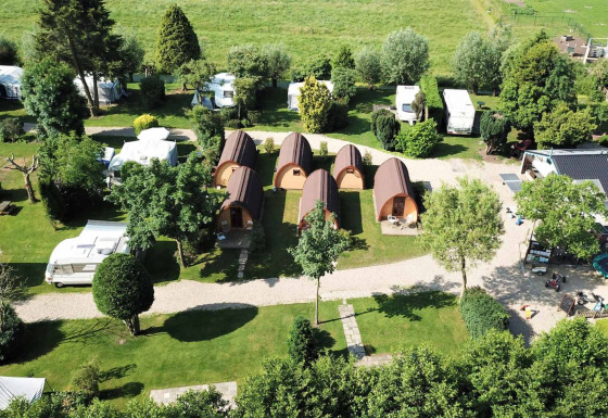 Luftfoto af Camping De Grienduil i Utrecht, Holland, med hytter, campingvogne og grønne omgivelser.