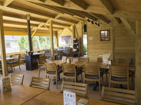 Comedor revestido en madera en Camping De Grienduil, Utrecht, Países Bajos, con mesas y sillas dispuestas.