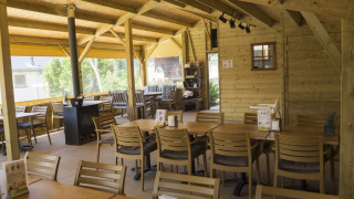 Comedor revestido en madera en Camping De Grienduil, Utrecht, Países Bajos, con mesas y sillas dispuestas.
