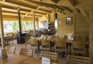 Holzverkleideter Essbereich im Ferienpark Camping De Grienduil, Utrecht, Niederlande, mit Tischen und Stühlen.