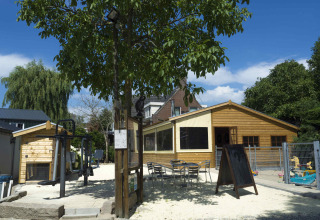 Buitenruimte met speeltuin en houten chalets bij Camping De Grienduil, vakantiepark in Utrecht, Nederland.