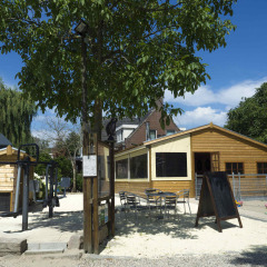 Zona exterior con parque infantil y cabañas de madera en Camping De Grienduil, parque vacacional en Utrecht.