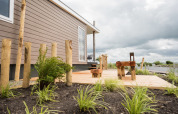 Waterlodge type 1 bij Vakantiepark Bergumermeer met houten terras en tuinstoelen aan het water.