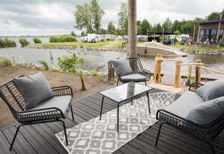 Acogedora terraza junto al agua con asientos modernos y vista al lago en Vakantiepark Bergumermeer, Países Bajos.