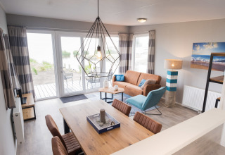 Sala de estar en Waterlodge tipo 1 en Vakantiepark Bergumermeer, Países Bajos, decoración moderna y ventanas grandes.