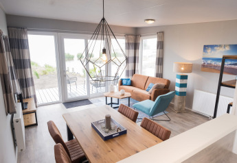 Soggiorno della Waterlodge tipo 1 al Vakantiepark Bergumermeer, Paesi Bassi, arredo moderno e grandi finestre.