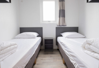 Værelse med to enkeltsenge, et lille natbord og moderne indretning i Waterlodge type 1, Vakantiepark Bergumermeer.