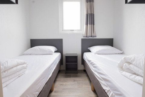 Habitación con dos camas individuales, mesita de noche y decoración moderna en Waterlodge type 1, Vakantiepark Bergumermeer.