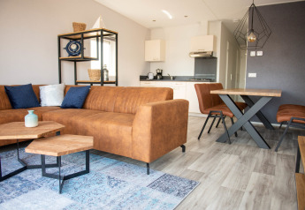 Moderne stue og køkken i Waterlodge type 1 på Vakantiepark Bergumermeer, Nederlandene, med lædersofa.