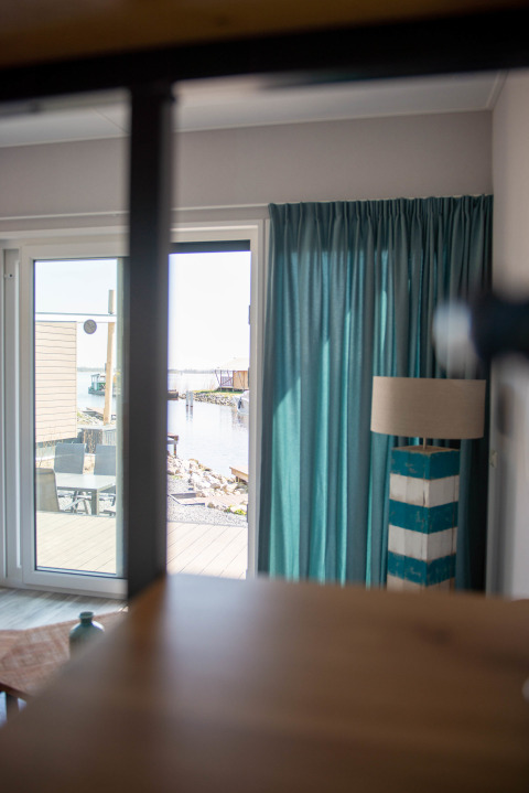 Blick aus Waterlodge Typ 1 im Vakantiepark Bergumermeer mit hellen Vorhängen und Außenterrasse.