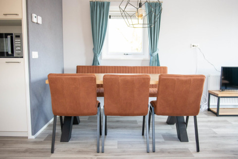 Dining area in Waterlodge type 1 at Vakantiepark Bergumermeer, with three brown chairs and a window.