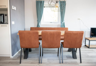 Dining area in Waterlodge type 1 at Vakantiepark Bergumermeer, with three brown chairs and a window.