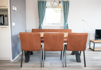 Dining area in Waterlodge type 1 at Vakantiepark Bergumermeer, with three brown chairs and a window.