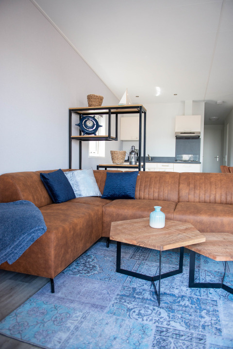 Wohnzimmer in Waterlodge Typ 1 im Vakantiepark Bergumermeer mit braunem Sofa und moderner Einrichtung.