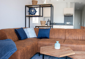 Moderne stue i Waterlodge type 1 på Vakantiepark Bergumermeer med brun sofa og dekorative puder.