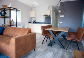 Stue og køkken i en moderne Waterlodge type 1 ved Vakantiepark Bergumermeer, Holland, med brune møbler.