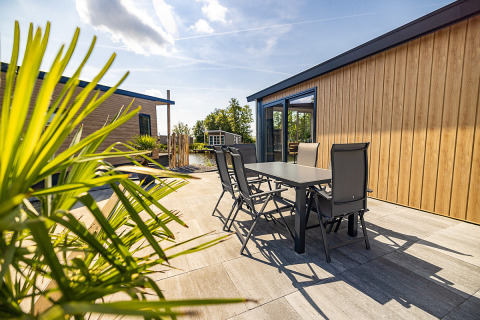 Moderne Terrasse bei Waterlodge Typ 2 im Vakantiepark Bergumermeer mit Gartentisch und Stühlen im Sonnenschein.