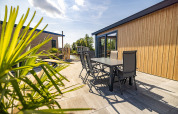 Terraza soleada en Waterlodge tipo 2 en Vakantiepark Bergumermeer con mesa y sillas modernas de exterior.