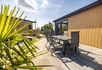 Terraza soleada en Waterlodge tipo 2 en Vakantiepark Bergumermeer con mesa y sillas modernas de exterior.
