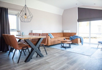 Soggiorno moderno nella Waterlodge tipo 2 al Vakantiepark Bergumermeer, con divano in pelle e tavolo.