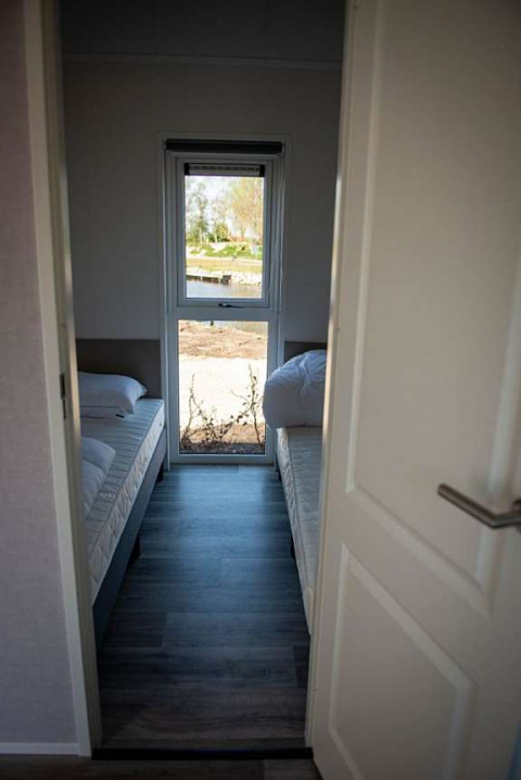 Narrow bedroom in Waterlodge type 2 at Vakantiepark Bergumermeer, Netherlands, with two single beds.