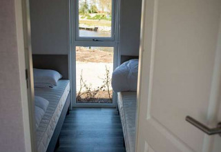 Schmales Schlafzimmer in einer Waterlodge Typ 2 im Vakantiepark Bergumermeer mit zwei Einzelbetten.