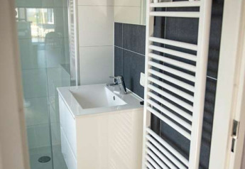 Petite salle de bains avec lavabo moderne, miroir, douche et sèche-serviettes blanc au Waterlodge type 2.