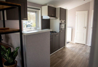 Moderne køkkenområde med trægulv og grå skabe i en Waterlodge på Vakantiepark Bergumermeer, Holland.