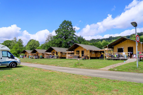 Tentes safari au Camping Walsheim en Allemagne, entourées de verdure sous un ciel bleu éclatant.