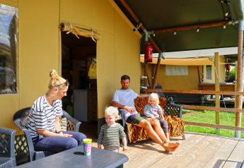 Familie slapper af foran safari telt på Camping Walsheim i Tyskland med børn på træterrasse.