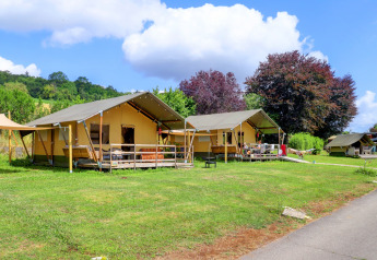 Safari-telt ved Camping Walsheim i Tyskland, omgivet af grønt græs og træer under blå himmel.