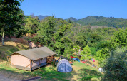 Campingområde i grønne bakker på Camping Pian D'Amora, feriepark i Toscana, Italien, med telte og bjerge.