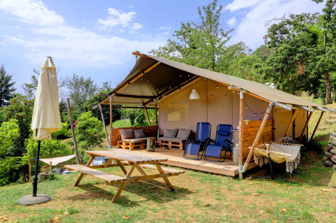 Tienda glamping con terraza de madera, mesa de picnic y hamaca en Camping Pian D'Amora, Toscana, Italia.