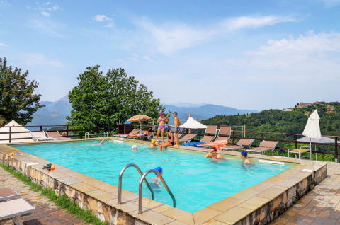 Swimming pool at Camping Pian D'Amora holiday park in Tuscany, Italy, with scenic hills and families relaxing.