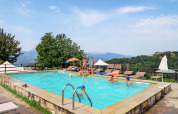 Swimming pool at Camping Pian D'Amora holiday park in Tuscany, Italy, with scenic hills and families relaxing.