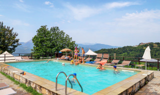 Swimming pool at Camping Pian D'Amora holiday park in Tuscany, Italy, with scenic hills and families relaxing.