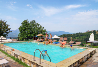 Piscina al Camping Pian D'Amora in Toscana, Italia, con vista panoramica sulle colline e ospiti che si rilassano.