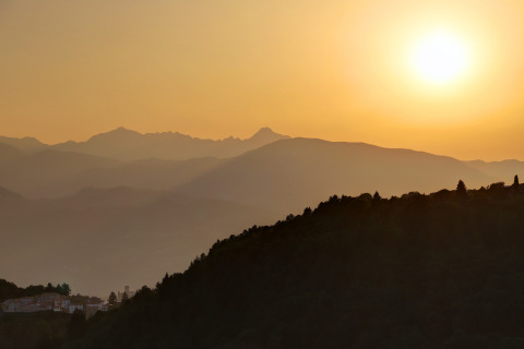 Sunset over gentle mountain ridges near Camping Pian D'Amora in Tuscany, Italy, with a tranquil atmosphere.