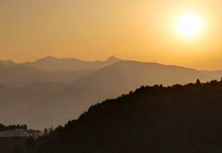 Sunset over gentle mountain ridges near Camping Pian D'Amora in Tuscany, Italy, with a tranquil atmosphere.