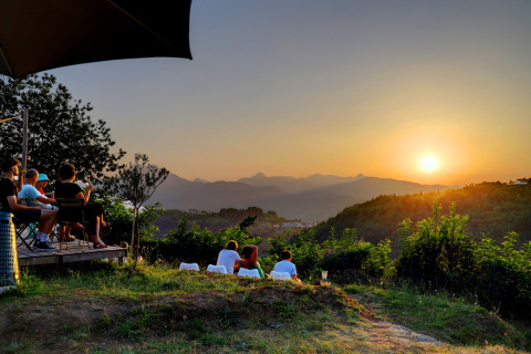Guests watch a scenic sunset over rolling hills at Camping Pian D'Amora holiday park in Tuscany, Italy.