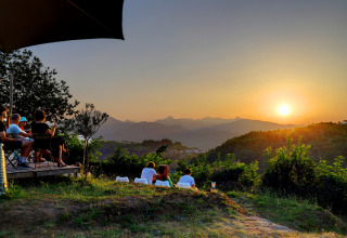 Ospiti ammirano il tramonto sulle colline dal Camping Pian D'Amora, parco vacanze in Toscana, Italia.
