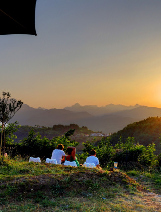 Guests watch a scenic sunset over rolling hills at Camping Pian D'Amora holiday park in Tuscany, Italy.