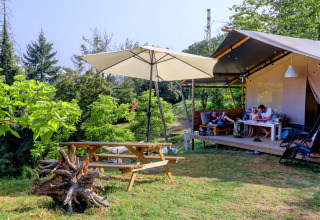 Family relaxing in a glamping tent with picnic table at Camping Pian D'Amora, Tuscany, Italy.