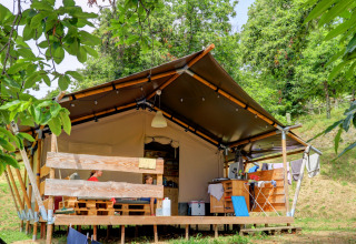 Tenda familiare al Camping Pian D'Amora in Toscana, Italia, circondata da alberi verdi e natura.