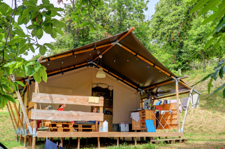 Familienzelt auf Camping Pian D'Amora in der Toskana, Italien, umgeben von Bäumen und Natur.