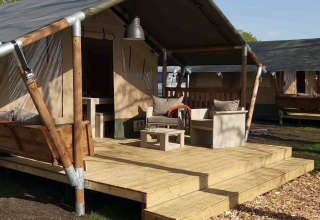Glamping tent met houten terras en comfortabele stoelen op Camping Batenstein in Utrecht, Nederland.