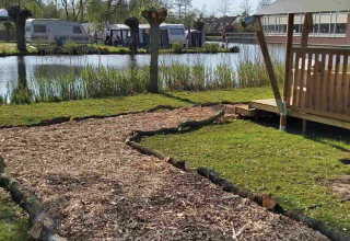 Camping area with caravans and a wooden shelter by a pond at Camping Batenstein, Utrecht, Netherlands.