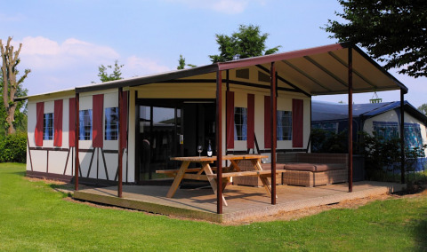 Safaritent Tentlodge bij Camping Vinkenhof in Nederland met overdekt terras, picknicktafel en loungebank.